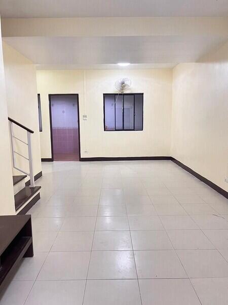 Empty living room with tiled floor and a window with a fan