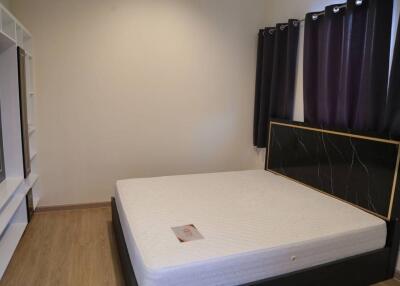 A bedroom with a bed, built-in shelves, and window curtains