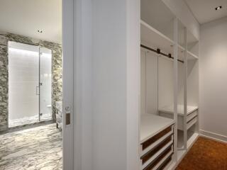 Bathtub and closet space with marble flooring and built-in storage units