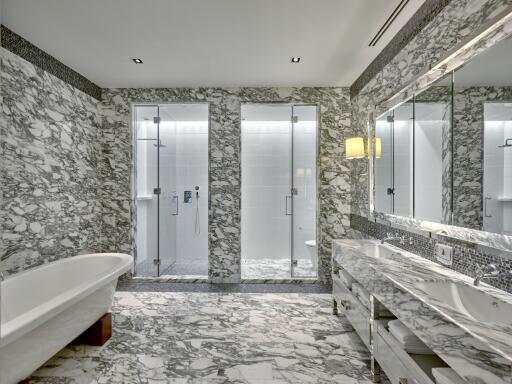 Luxurious bathroom with marble tiles, large mirror, double sink, bathtub, and walk-in shower