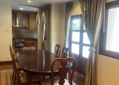 Dining room with wooden table and chairs, pendant lights, curtains, and windows