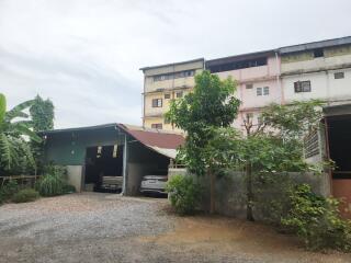 Front view of a residential building with parking and greenery