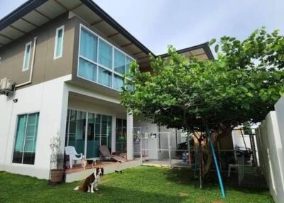 Two-story residential building with green lawn and sitting area