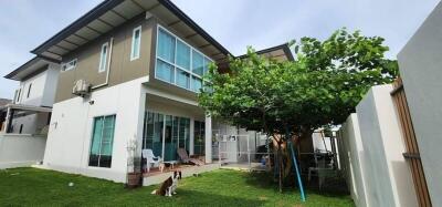 Two-story residential building with green lawn and sitting area