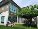 Two-story residential building with green lawn and sitting area