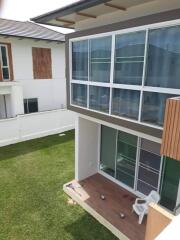 Exterior view of a modern two-story house with large windows and a small patio.