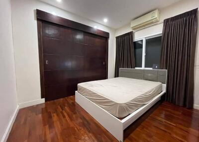 Bedroom with a wooden floor, dark curtains, and a large closet