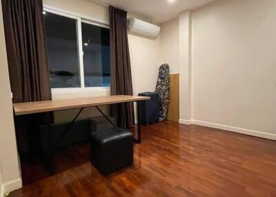 Spacious bedroom with wooden flooring and a desk near the window