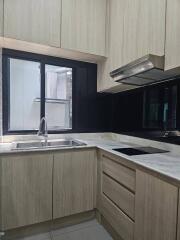 Modern kitchen with window, sink, stovetop, and overhead cabinets