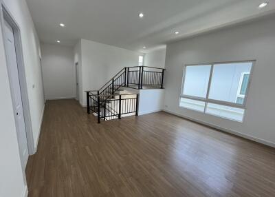 Spacious open living area with wooden flooring and modern staircase