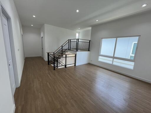 Spacious open living area with wooden flooring and modern staircase