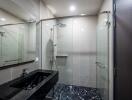 Modern bathroom with glass shower enclosure and black marble sink counter