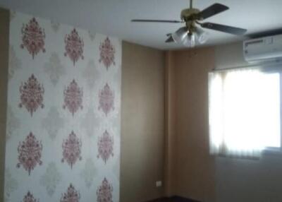 Spacious bedroom with wooden flooring and patterned feature wall