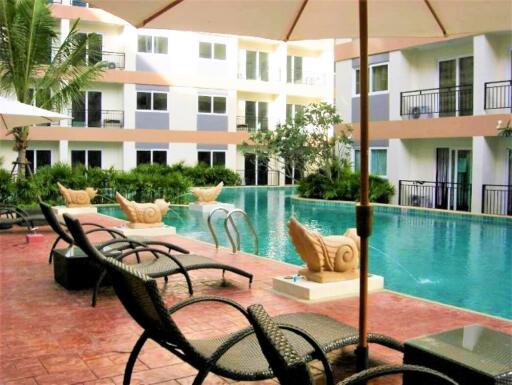 Swimming pool area with lounge chairs and apartments in the background