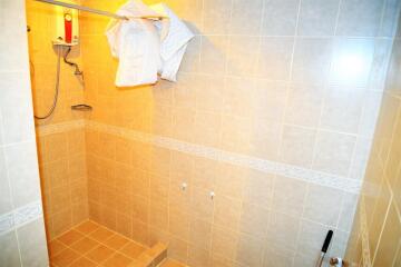 Well-lit tiled shower area with water heater