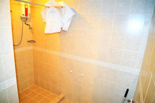 Well-lit tiled shower area with water heater