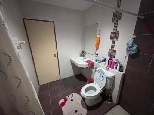 Bathroom with white fixtures, a mirror, and a variety of toiletries