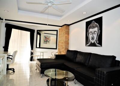 Modern living room with black sectional sofa, glass coffee table, and wall art