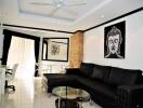 Modern living room with black sectional sofa, glass coffee table, and wall art