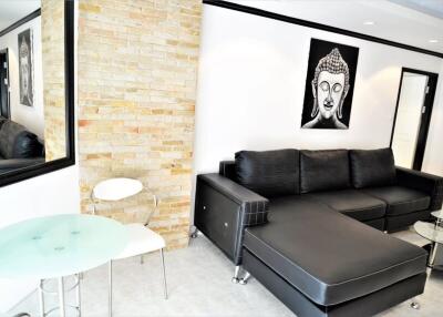 Modern living room with black leather sectional sofa, decorative wall art, and a small glass table and chairs