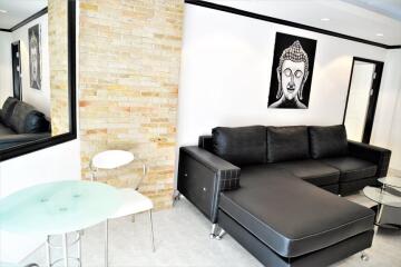 Modern living room with black leather sectional sofa, decorative wall art, and a small glass table and chairs