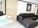 Modern living room with black leather sectional sofa, decorative wall art, and a small glass table and chairs