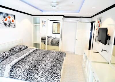 Modernly decorated bedroom with a large bed and mirrored wardrobe