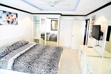 Modernly decorated bedroom with a large bed and mirrored wardrobe