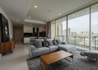 Modern living room with a city view, grey sofa, coffee table, and open kitchen