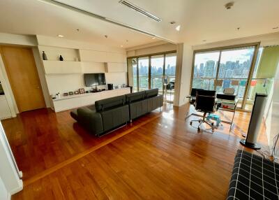 Modern living room with wooden floor, large windows, and city view