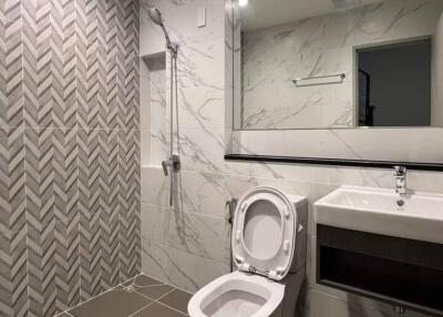 Modern bathroom with large mirror, toilet, sink, and walk-in shower.