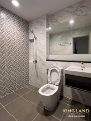 Modern bathroom with large mirror, toilet, sink, and walk-in shower.