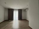 Spacious empty living room with large window and curtains