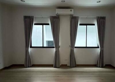 Bedroom with two windows, curtains, and air conditioning