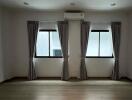 Bedroom with two windows, curtains, and air conditioning