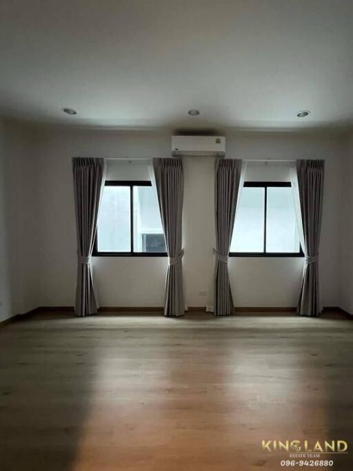 Bedroom with two windows, curtains, and air conditioning