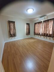 Empty bedroom with wooden flooring and curtains