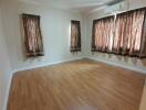 Empty bedroom with wooden flooring and curtains