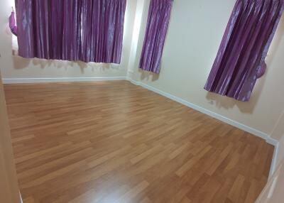 Bedroom with wooden flooring and purple curtains