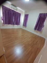 Bedroom with wooden flooring and purple curtains