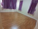 Bedroom with wooden flooring and purple curtains