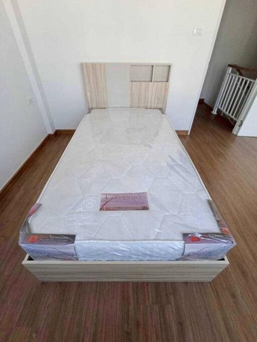 Simple bedroom with a single bed and wooden flooring