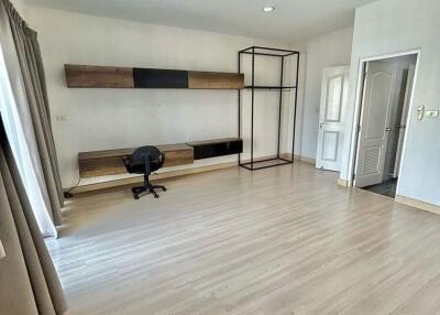 Spacious bedroom with wooden flooring, desk, and ample natural light