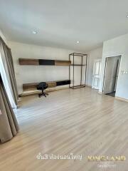 Spacious bedroom with wooden flooring, desk, and ample natural light