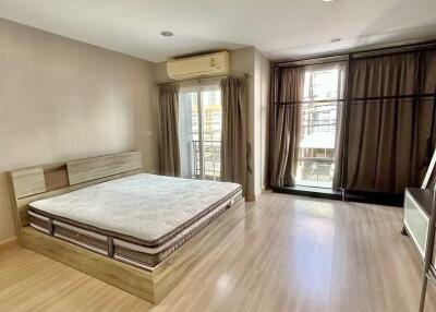 Spacious bedroom with wooden floor, large bed, and balcony access