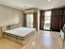 Spacious bedroom with wooden floor, large bed, and balcony access