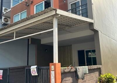 Front view of a multi-story residential building with a gated entrance and small driveway.