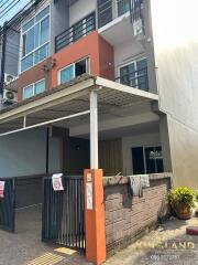 Front view of a multi-story residential building with a gated entrance and small driveway.