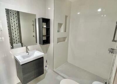 Modern bathroom with sink, mirror, shelves, and toilet