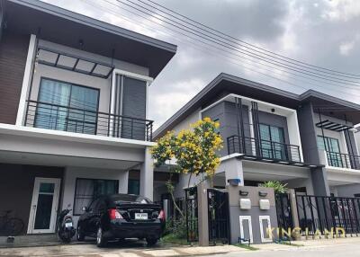 Two modern two-story houses with garages and a tree in between